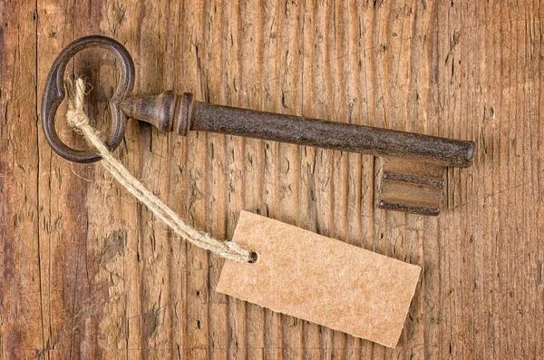 Llave vieja con una etiqueta en una tabla de madera — Foto de Stock