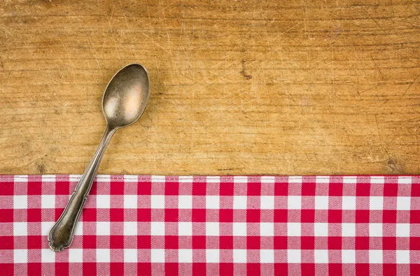 Silver spoon on a wooden board with a checkered tablecloth — Stock Photo, Image