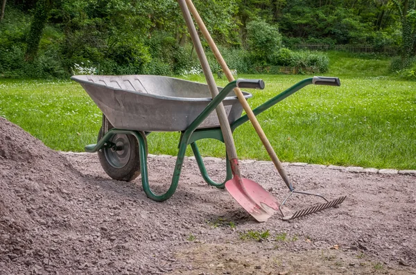 Kruiwagen met schop en rake — Stockfoto