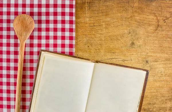Tahta kaşık ve bir ahşap tahta kareli bir masa örtüsü ile ilgili kitap — Stok fotoğraf