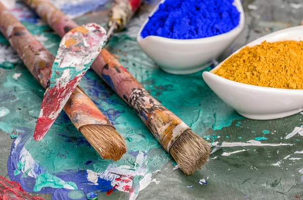 Ahşap palet üzerinde fırça, spatula ve renk pigmentleri — Stok fotoğraf