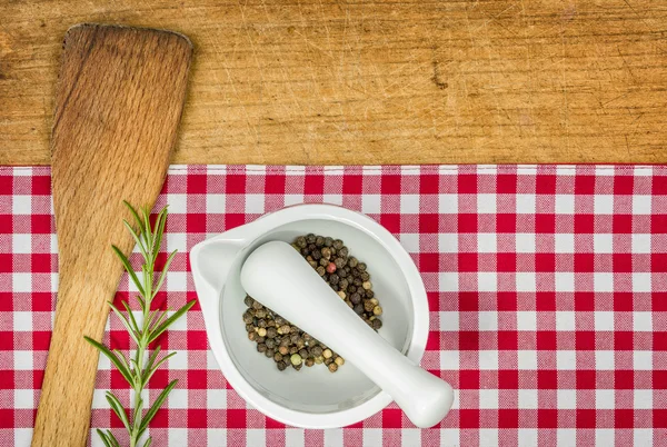 Wooden spoon and mortar on a wooden board with checked tablecloth — Stock Photo, Image