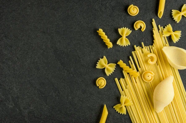 Different types of pasta on a slate background — Stock Photo, Image