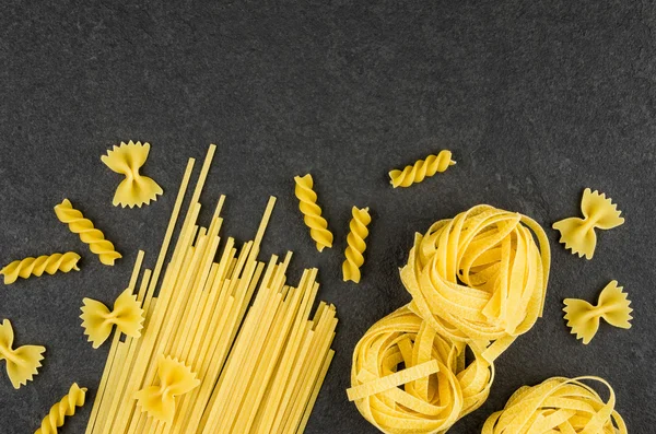 Different types of pasta on a slate background — Stock Photo, Image