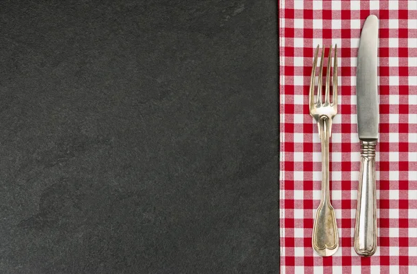 Kırmızı kareli masa örtüsü ile kayrak bir plaka üzerinde gümüş — Stok fotoğraf