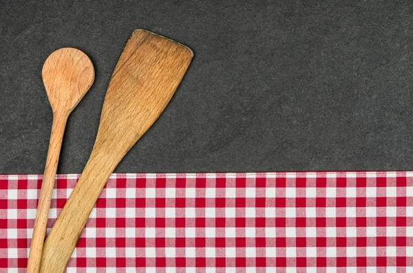 Wooden spoon on a slate plate with a red checkered tablecloth — Stock Photo, Image