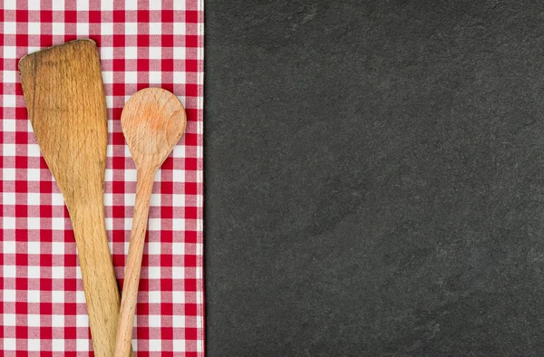 Cuchara de madera en un plato de pizarra con un mantel a cuadros rojo — Foto de Stock