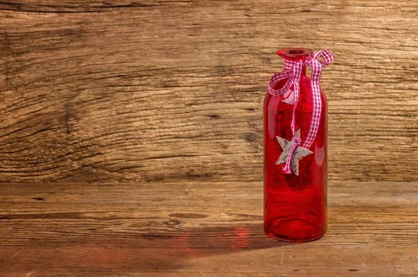 Botella de vidrio rojo sobre fondo de madera — Foto de Stock