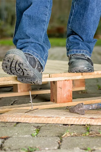 Werknemer met veiligheid laarzen stappen op een nagel — Stockfoto