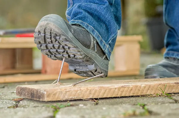 Travailleur avec des bottes de sécurité marche sur un clou — Photo