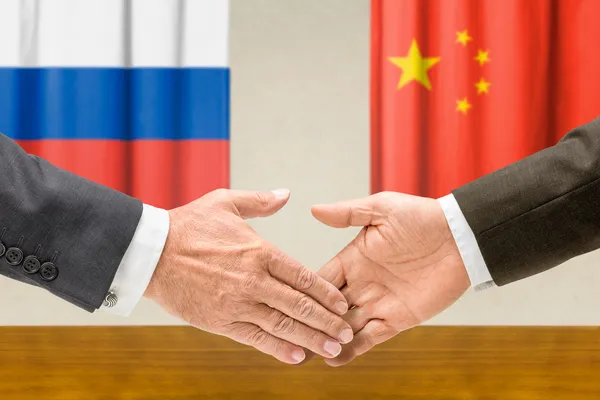 Представники Росії та Китаю потиснути один одному руки — стокове фото