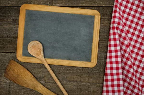 Empty blackboard with wooden spoons and red checkered tablecloth — Stock Photo, Image