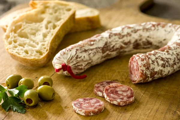 Salami with baguette and green olives — Stock Photo, Image
