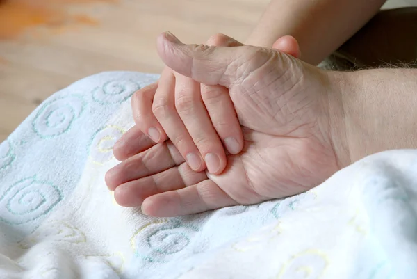 Joven sosteniendo la mano de un anciano — Foto de Stock