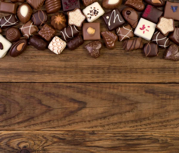 木製の背景にさまざまなチョコレート — Stock fotografie