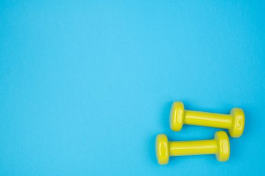 Mavi arkaplanda sarı dambıllar, kopyalama alanı olan üst görünüm 