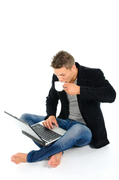 Jovem trabalhando no laptop e bebendo café — Fotografia de Stock