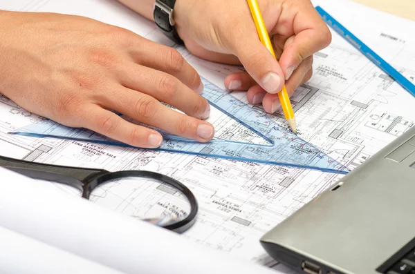 Man working with pencil and a magnifier on blueprints — Stock Photo, Image