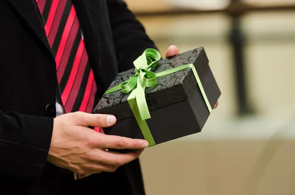 Les mains de l'homme présentant une boîte cadeau — Photo