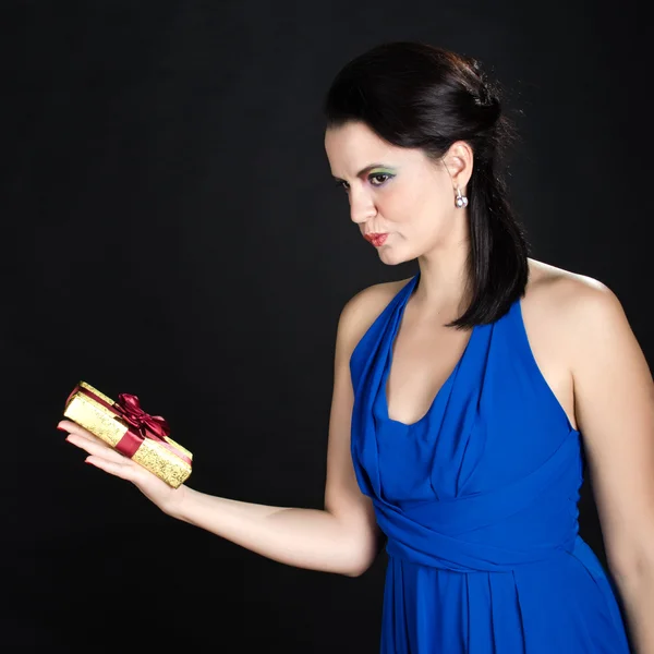 Beautiful woman showing a golden gift box — Stock Photo, Image