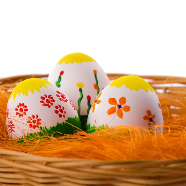 Tres coloridos huevos de Pascua pintados en una cesta —  Fotos de Stock