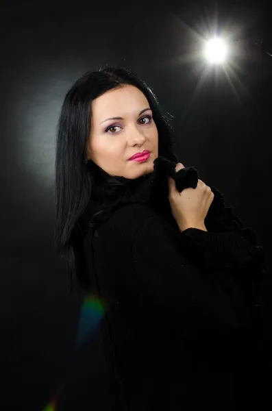 Schöne Brünette posiert vor schwarzem Hintergrund mit Rampenlicht — Stockfoto