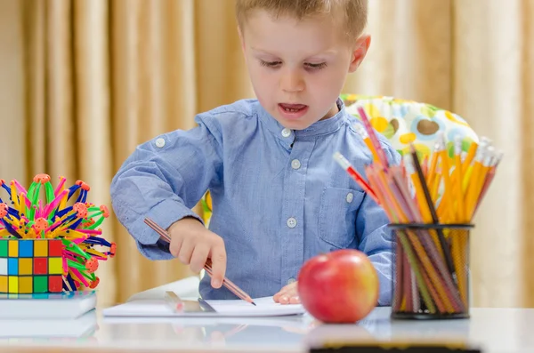 Beautiful child writing with a red pen — Stock Photo, Image