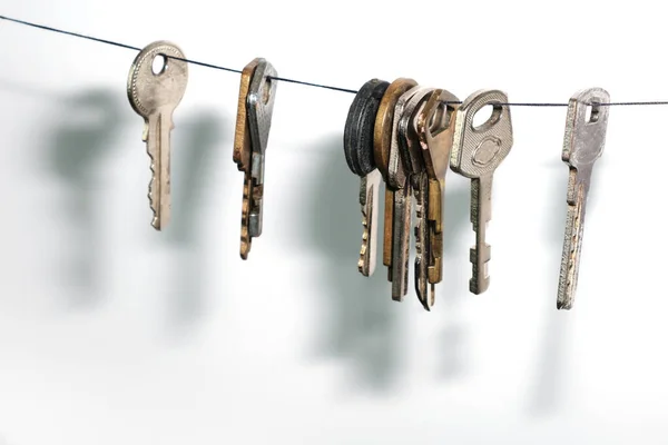 Different Keys Different Locks Hanging String Drop Shadow White Wall — Stock Photo, Image