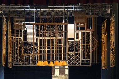 Tiyatro sahnesinde siyah arkaplanı olan soyut sarı metal yapılar.