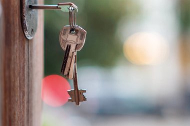 Arka planda bulanık ışıklar, seçici odak ile kapı anahtar deliğinde anahtarlık