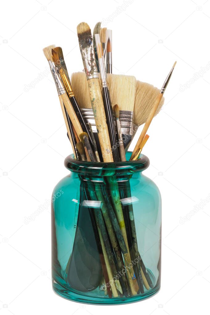 Various professional paint brushes in the green glass jar, isolated on white background