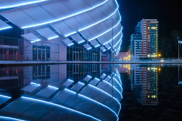 Nachtansicht Der Beleuchteten Modernen Gebäudekonstruktion Die Sich Auf Einer Wasseroberfläche — Stockfoto