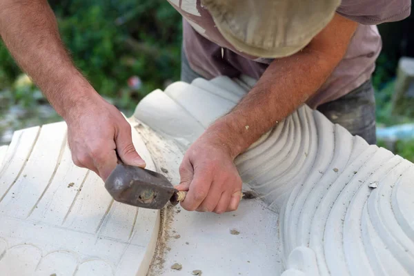 Close up of sculptor hands is working on a white stone