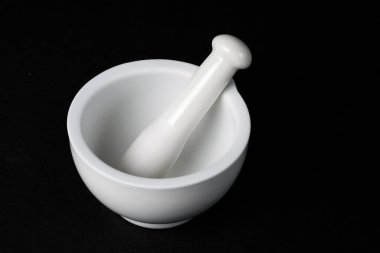 Koyu yüzeyde beyaz porselen havan ve tokmak.