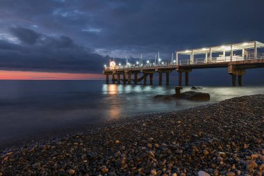 Geceleri kayalık sahilde aydınlatılmış rıhtım.