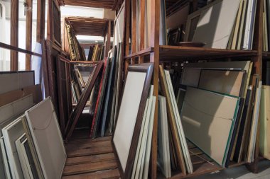Resim, çerçeve ve sanat malzemeleriyle dolu ahşap raflar. Sanat galerisi deposu