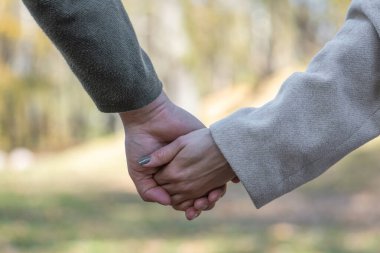 Aşk, ilişki, doğa konsepti. Soğuk ve güneşli bir günde, erkek ve kadının yakın plan çekimleri birbirini bulanık doğa arka planında tutar.