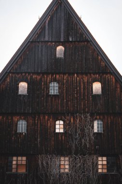 Terk edilmiş eski ahşap ev. Pencereli koyu kahverengi bir ahır. Köyde yıpranmış bir ev. Kırsal mimari. Yaşlanmış kereste evi. Taşra simgesi.