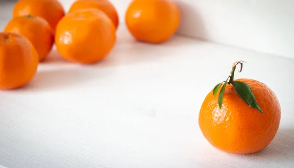 Tatlı narenciye meyveleri. Beyaz ahşap arka planda olgun mandalinalar. Tüm kavramlara karşı bir. Farklı bir konsept. Yapraklı bir mandalina ve yapraksız bir meyve grubu. C vitamini kavramı. 