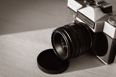 Beyaz ahşap raftaki eski fotoğraf makinesi, siyah beyaz. Retro tarzı kamera. Klasik fotoğrafçılık. Eski moda teknoloji. Antika fotoğraf ekipmanları. Retro optik ekipman.