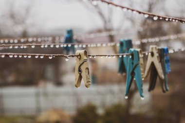 Giysiler tele iğnelenmiş. İğneli ve yağmur damlalı ip. Çamaşır konsepti. Köyde yağmurlu bir gün. Kırsal yaşam. Su damlaları ve raptiyeler kapanıyor. Kırsal alan. Bahar havası kavramı. 