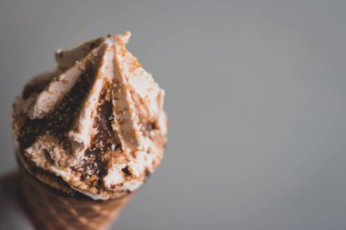 Fotokopi alanı olan gri duvar arkaplanlı dondurma külahı. Gözlemeli karamel dondurma. Kremalı tatlı. Soğuk tatlıyı tazeliyorum. Dondurma eritiyorum. Yaz yaşam tarzları. Tatlı yemek konsepti. 