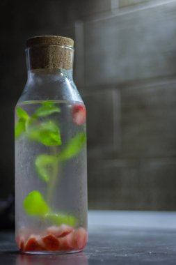 Suda nane ve çilek. Donmuş şişede nane yaprakları ve doğranmış çilek. Antioksidan içeceği. Taze yaz içkileri. Ev yapımı detoks suyu. Naneli limonata. Buzlu içecek. Yenileme konsepti.