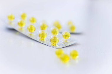 Beyaz arka planda sarı haplar. Sağlık hizmeti konsepti. Haplar ve kapsüller. İlaç ve eczane konsepti. Sarı haplar. Vitaminler kapsüllerde. Tıbbi tedavi. Haplar ve uyuşturucular.