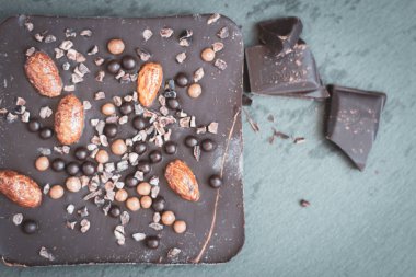 Badem ve kahve çekirdekli koyu çikolata. Siyah tabakta kırılmış çikolata. Tatlı yemek. Fındıklı siyah çikolata. Kahve ürünü.. 