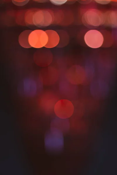 Red light, blurred. Light in the night, unfocused. Glowing spots in dark. Red light background. Fairytale background. Shiny circles in dark. Magical dust concept. Glimmer effect.