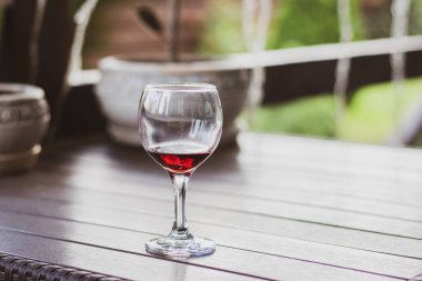 Ahşap masada bir kadeh kırmızı şarap. Verandada şarap kadehi. Alkolik içecekler. Summer rahatla. Provence 'deki üzüm bağı. Kırmızı şarap konsepti. Şarap konsepti..