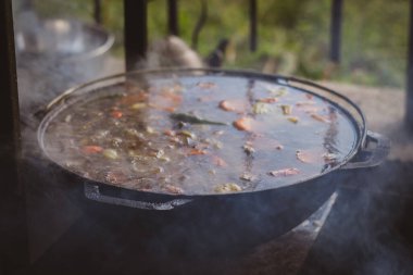 Tavada kaynatılmış çorba. Çaydanlık yanıyor. Turistik yiyecekler. Ana yemek hazırlığı. Kaynamış et çorbası. Kamp ateşinde esrar. Piknik yemeği. Çorba tarifi. 