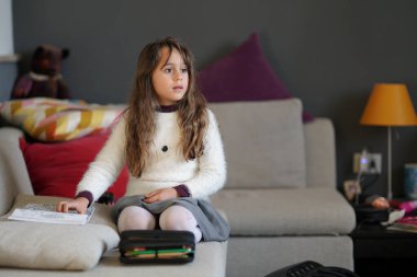 6-7 yaşlarında genç bir kız, yana bakıyor.