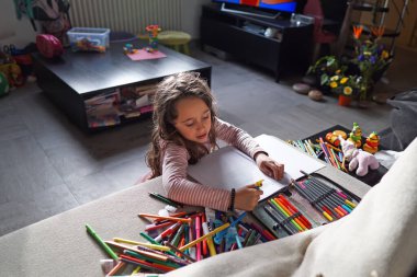 6-7 yaşlarındaki genç kız çiziyor, yazıyor.